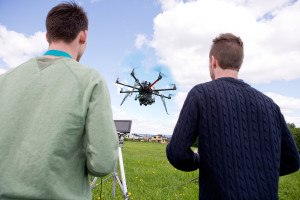 A pilot and photographer operating a UAV photography drone in an open field