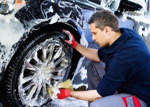 Man worker washing car's alloy wheels on a car wash